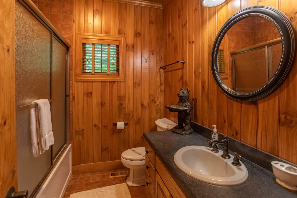 A warm, inviting ensuite bathroom with natural wood paneling, a sink with a polished mirror, and a decorative figurine, creating a personal and luxurious space for self-care and relaxation.