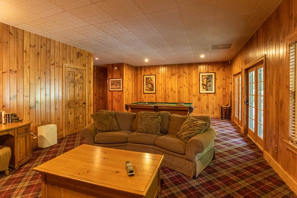 A welcoming lounge area is shown, with a comfortable sofa, a pool table ready for play, wood-paneled walls, and a sturdy coffee table. The room radiates a relaxed, social vibe ideal for game nights or movie marathons.